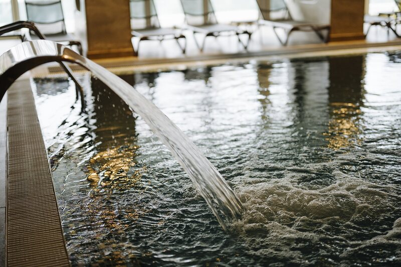 Indoor pool with water feature spout and lounge chairs